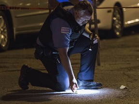 In this Sunday, July 6, 2014 photo, a Chicago police officer checks on evidence at the scene where a man was shot in Chicago's Uptown neighborhood. (AP Photo/Sun-Times Media, Alex Wroblewski)