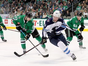 Stars’ Esa Lindell and Jets’ Patrik Laine search for the puck during a game earlier this season at American Airlines Center in Dallas. (GETTY IMAGES)