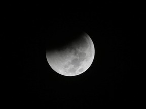 In this Saturday Aug. 28, 2018 file photo, Earth starts to cast its shadow on the moon during a complete lunar eclipse seen from Jakarta, Indonesia.