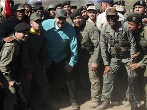 In this photo released to the media by Miraflores presidential palace press office, Venezuelan President Nicolas Maduro, wearing a blue shirt, third from left in the front row, poses for photos with soldiers as he visits Ft. Paramacay in Carabobo state, Venezuela, Sunday, Jan. 27, 2019. Opposition lawmaker Juan Guaido has declared himself Venezuela's legitimate leader, as embattled socialist Maduro holds the reins of power. (Marcelo Garcia/Miraflores presidential palace press office via AP)