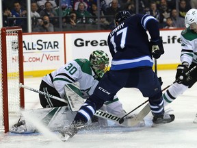 Jets centre Adam Lowry (centre) bangs at a loose puck in front of Dallas Stars goaltender Ben Bishop with John Klingberg defending in on Sunday night. Kevin King/Winnipeg Sun/Postmedia Network