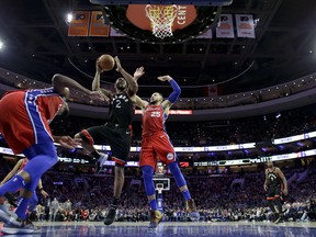 Raptors' Kawhi Leonard goes up for a shot between Philadelphia 76ers' Ben Simmons (right) and Joel Embiid during Tuesday's game. (AP PHOTO)