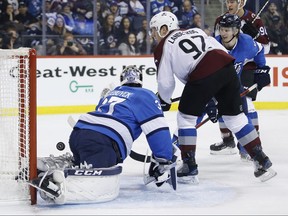 Colorado Avalanche's Gabriel Landeskog scores on Winnipeg Jets goaltender Connor Hellebuyck as Jacob Trouba looks on during their game in Winnipeg on Thursday. (THE CANADIAN PRESS)