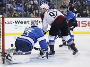 Colorado Avalanche's Gabriel Landeskog scores on Winnipeg Jets goaltender Connor Hellebuyck as Jacob Trouba looks on during their game in Winnipeg on Thursday. (THE CANADIAN PRESS)
