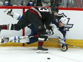 Arizona Coyotes defenceman Alex Goligoski (front) sends Winnipeg Jets centre Adam Lowry to the ice in Glendale, Ariz. Sunday night. The Jets lost to the Coyotes 3-1. (AP)