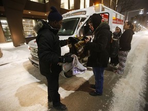 Peter Oyeniyi, a van outreach worker with the Salvation Army Extreme Environment Response Vehicle, assists people with blankets on Winnipeg streets who are suffering under the extreme temperatures in the early hours of Saturday morning.