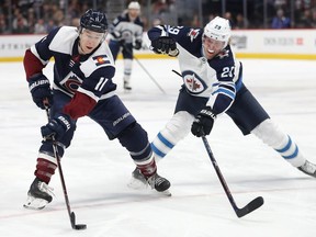 Matt Calvert of the Colorado Avalanche advances the puck against Patrik Laine of the Winnipeg Jets at the Pepsi Center on Friday in Denver.