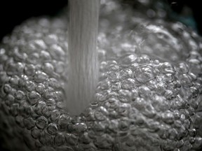 Running water creates bubbles as it fills a glass.