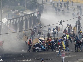 Demonstrators clash with authorities on the fence of La Carlota Air Base in Caracas, Venezuela, on June 24, 2017 after more than 70 people were killed during almost 90 days of protests seeking President Nicolas Maduro's removal. (AP Photo/Ariana Cubillos)