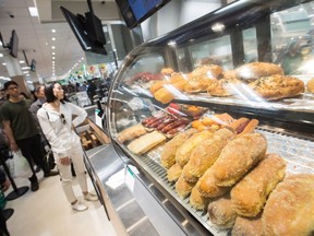 People line up at an Asian street food area at T&T Supermarket's newest location, in Richmond, B.C., on Tuesday August 21, 2018. Grocery stores increasingly blur the line between supermarkets and restaurants with large chains adding take-out meals to their shelves, hot food counters where chefs make dishes to order and even full-service restaurants. Dubbed grocerants, these combination spaces serve a time-strapped population that values convenience.