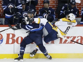 Winnipeg Jets' Brandon Tanev (13) checks Nashville Predators' Kyle Turris (8) during first period NHL action in Winnipeg on Friday, March 1, 2019.