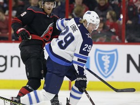 Carolina Hurricanes' Dougie Hamilton (19) and Winnipeg Jets' Patrik Laine (29), of Finland, chase the puck during the first period of an NHL hockey game in Raleigh, N.C., Friday.