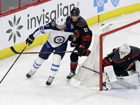 Carolina Hurricanes' Trevor van Riemsdyk (57) and goalie Curtis McElhinney defend against Winnipeg Jets' Adam Lowry (17) during the third period of an NHL hockey game in Raleigh, N.C., Friday, March 8, 2019.