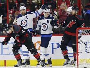 Winnipeg Jets' Blake Wheeler (26) and Mark Scheifele celebrate following Wheeler's goal while Carolina Hurricanes' Dougie Hamilton (19) and Jaccob Slavin, right, skate away during the first period on Friday in Raleigh, N.C.  (AP Photo/Gerry Broome)
