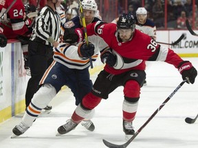 Senators centre Colin White (right) collides with Oilers right wing Alex Chiasson along the boards during second period NHL action in Ottawa, Thursday, Feb. 28, 2019.