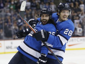 Winnipeg Jets' Mathieu Perreault (left) and Jack Roslovic celebrate Perreault's go ahead goal on Calgary Flames goaltender Mike Smith  in Winnipeg on Saturday. (The Canadian Press)