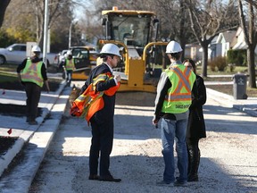Mayor Brian Bowman pulls on a safety vest during a visit to the site of an asphalt reconstruction project on Ravenhill Road in the Valley Gardens area of Winnipeg on Thu., Oct. 22, 2015. Kevin King/Winnipeg Sun/Postmedia Network