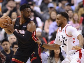 Miami Heat guard Dwyane Wade looks for a pass as Toronto Raptors' Norman Powell defends during Sunday's game. (THE CANADIAN PRESS)