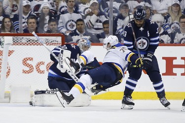 St. Louis Blues centre Oskar Sundqvist (70) falls in front of Winnipeg Jets goaltender Connor Hellebuyck (37) as Winnipeg Jets defenceman Dustin Byfuglien (33) defends during second period NHL playoff action in Winnipeg on Wednesday, April 10, 2019. THE CANADIAN PRESS/John Woods