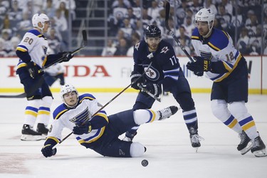Winnipeg Jets centre Adam Lowry (17) battle against St. Louis Blues centre Ivan Barbashev (49) and Zach Sanford (12) during first period NHL playoff action in Winnipeg on Wednesday, April 10, 2019. THE CANADIAN PRESS/John Woods