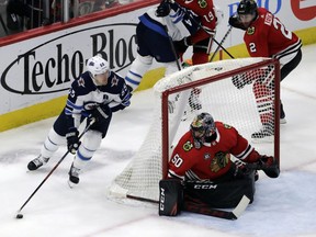 Winnipeg Jets center Mark Scheifele, left, controls the puck as he looks to score on Chicago Blackhawks netminder Corey Crawford. The Jets won 4-3 in overtime. (AP)