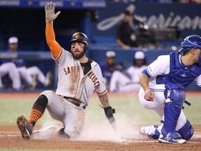 San Francisco Giants’ Kevin Pillar slides across home plate past Blue Jays catcher Luke Maile to score a run in the second inning on Tuesday night at Rogers Centre. Pillar, an ex-Jay, went 1-for-4 with one RBI in his team’s 7-6 win. (GETTY IMAGES)