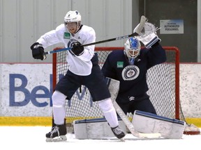 Jets’ Andrew Copp (left) and Laurent Brossoit scramble to avoid a high shot during practice on Monday. (KEVIN KING/WINNIPEG SUN)