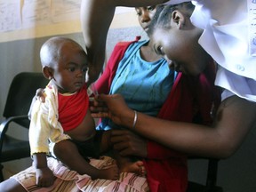 In this photo taken on Thursday, March 21, 2019, a volunteer nurse examines six-moth-old Sarobidy, who is infected with measles, while her mother Nifaliana Razaijafisoa looks on, at a healthcare centre in Larintsena, Madagascar.