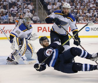 WINNIPEG, MANITOBA - APRIL 10: Joel Edmundson #16 of the St. Louis Blues dumps Adam Lowry #17 of the Winnipeg Jets in Game One of the Western Conference First Round during the 2019 NHL Stanley Cup Playoffs at Bell MTS Place on April 10, 2019 in Winnipeg, Manitoba, Canada. (Photo by Jason Halstead/Getty Images)