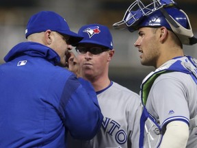Blue Jays pitcher Trent Thornton, centre, gets a visit at the mound from pitching coach Pete Walker, left, as catcher Luke Maile talks during first inning MLB action Wednesday, April 17, 2019, in Minneapolis.