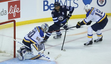 Winnipeg Jets defenceman Dustin Byfuglien (centre) shovels the puck at St. Louis Blues goaltender Jordan Binnington as he is checked by Jay Bouwmeester during Game 1 of Round 1 of the NHL playoffs in Winnipeg on Wed., April 10, 2019. Kevin King/Winnipeg Sun/Postmedia Network