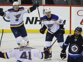 St. Louis Blues centre Tyler Bozak (right) celebrates his game-winning during Game 1 of Round 1 of the NHL playoffs against the Jets with Robert Thomas (left) and Robert Bortuzzo (bottom) on Wednesday. Kevin King/Winnipeg Sun/Postmedia Network