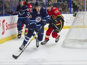 Winnipeg Jets Leon Gawanke (left) picks up the puck from behind his net while pressured by Calgary Flames Adam Ruzicka during NHL preseason hockey action at the Young Stars Classic held at the South Okanagan Events Centre in Penticton, BC, September, 11, 2017. On Thursday, the Jets announced they've signed Gawanke to an entry level contract. (Richard Lam/PNG