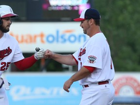 Former Goldeyes first basemen Eric Aquilera (left) fist-bumps first-base coach Tom Vaeth during American Association action last June. Vaeth is in his 17th season with the Winnipeg club and is primed to become a manager. (KEVIN KING/WINNIPEG SUN FILES)