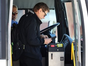A transit rider prepares to pay his fare at a stop on Osborne Street in Winnipeg on Monday. The Amalgamated Transit Union 1505, without a contract since January, is undertaking job action on Tuesday where its drivers would not enforce fare payment.