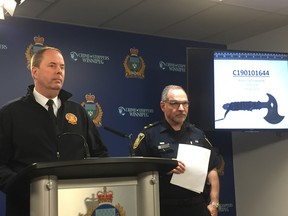 Winnipeg Fire Paramedic Service Assistant Chief Mark Reshaur (left) and Winnipeg Police Service spokesperson Const. Rob Carver address the media at a briefing on Friday, at police headquarters with a image of a hatchet on the screen in the background.