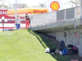 One person sorts through disheveled belongings in the shade of a bridge while others walk in the sun above. 
Tuesday, May 14/2019 Winnipeg Sun/Chris Procaylo/stf