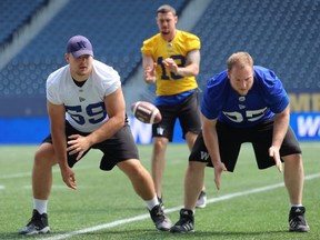 Centre Michael Couture (left) snaps to quarterback Bryan Bennett (centre) as he and defensive lineman Jake Thomas provide protection during the Winnipeg Blue Bombers walkthrough at IG Field on Wed., May 30, 2019. The Bombers face the Edmonton Eskimos in pre-season action on Friday. Kevin King/Winnipeg Sun/Postmedia Network