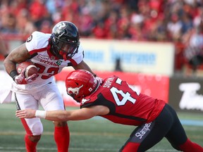 Redblacks’ Mossis Madu (left) is tackled by Stampeders’ Fraser Sopik during Saturday night’s game in Calgary. (JIM WELLS/POSTMEDIA NETWORK)