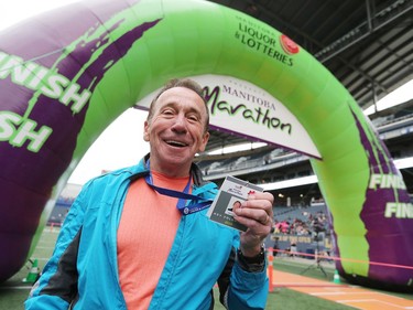 Running Room founder John Stanton helps to hand out finisher medals in the finish area at the 41st annual Manitoba Marathon in Winnipeg, Man., on Sunday, June 16, 2019.