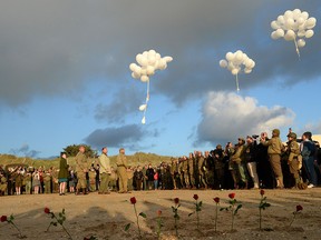 French WWII enthusiasts of the group Overlord 76 plant red roses in the sand and release white balloons in tribute to U.S. soldiers who died on Utah Beach in Sainte-Marie-du-Mont, June 6, 2019. (JEAN-FRANCOIS MONIER/AFP/Getty Images)