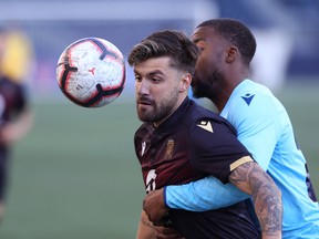 Valour FC’s Michael Petrasso (left) keeps his eye on the ball as he is held by HFX Wanderers FC’s Ndzemdzela Langwa on Wednesday night at IG Field. (KEVIN KING/WINNIPEG SUN)