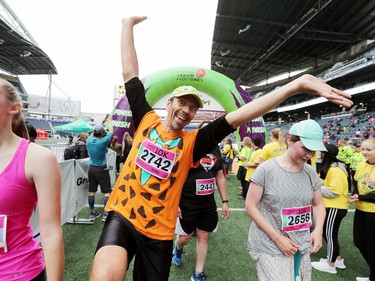 Winnipeg resident Carl Enns, who is dressed up like Fred Flintstone, displays planty of enthusiasm after completing the 10 kilometre run at the 2019 Manitoba Marathon in Winnipeg, Man., on Sunday, June 16, 2019.