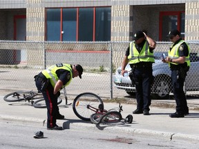Police inspect at the scene of a fatal motor vehicle collision with a cyclist near the intersection of Higgins Avenue and King Street in Winnipeg on Tuesday.