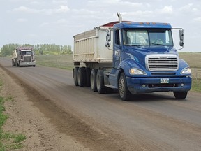 Two fully-loaded gravel hauling trucks drive down Currie's Landing in the RM of Cornwallis, Man. A Manitoba company says it has developed a product to make travelling gravel roads safer.