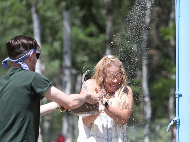 Kyleen Normandau (right) and her friend Nash Bockstael have an impromptu water fight at an outdoor shower to cool off while attending the 46th annual Winnipeg Folk Festival at Birds Hill Provincial Park, north east of Winnipeg, Man., on Saturday, July 13, 2019. The temperature hit 28 degrees Celsius by mid afternoon. This year's Folk Festival runs July 11 to 14, 2019.