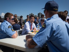 Prime Minister Justin Trudeau, back centre, talks with members of the Canadian Coast Guard after an announcement at the Kitsilano Coast Guard Base, in Vancouver, on Monday July 29, 2019. THE CANADIAN PRESS/Darryl Dyck