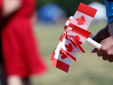 A volunteer holds souvenir flags to be distributed at Assiniboine Park in Winnipeg on Mon., July 1, 2019. Kevin King/Winnipeg Sun/Postmedia Network