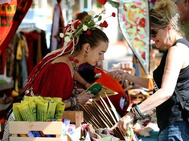 A street vendor with flowers in her hair helps a customer during the Canada Day Street Festival on Osborne Street in Winnipeg on Mon., July 1, 2019. Kevin King/Winnipeg Sun/Postmedia Network
