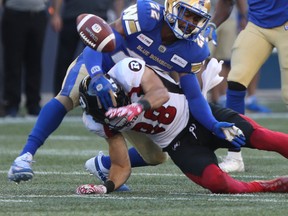 Winnipeg Blue Bombers Chandler Fenner (22) controls Ottawa Redblacks' Brad Sinopoli on Friday night. Winnipeg Sun/Chris Procaylo